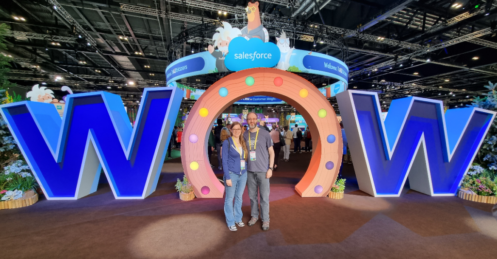 Two people posing in front of "WOW" sign at Salesforce World Tour